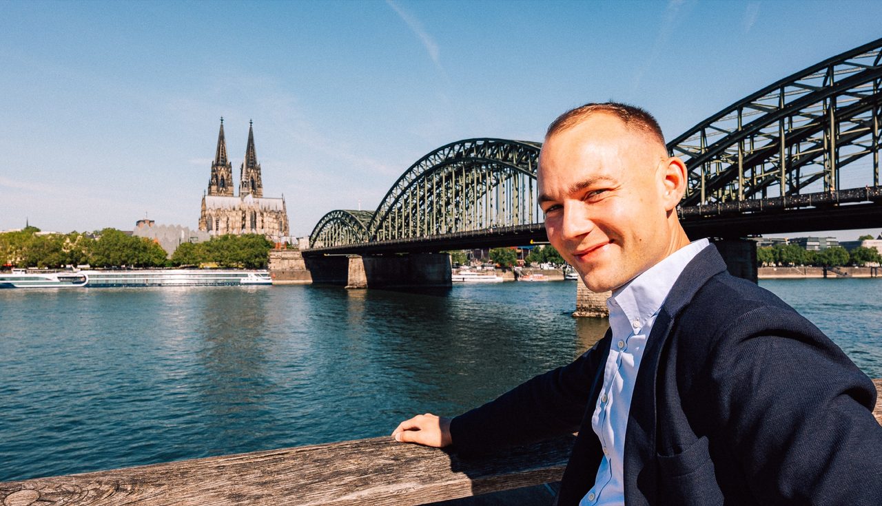 Leonard Kordowski am Rhein mit Dom und Hohenzollernbrücke im Hintergrund