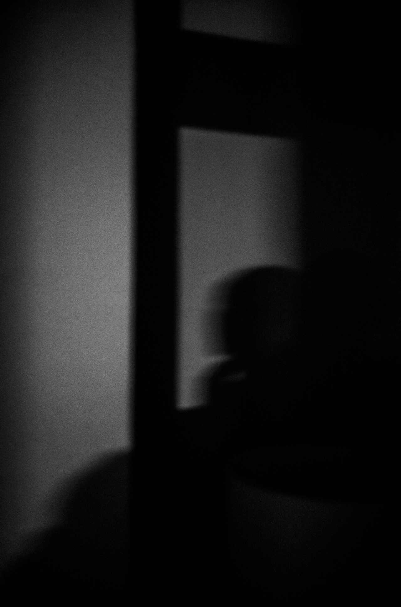 Der unscharfe Schatten einer Person fällt auf eine geometrisch beleuchtete Wand.
