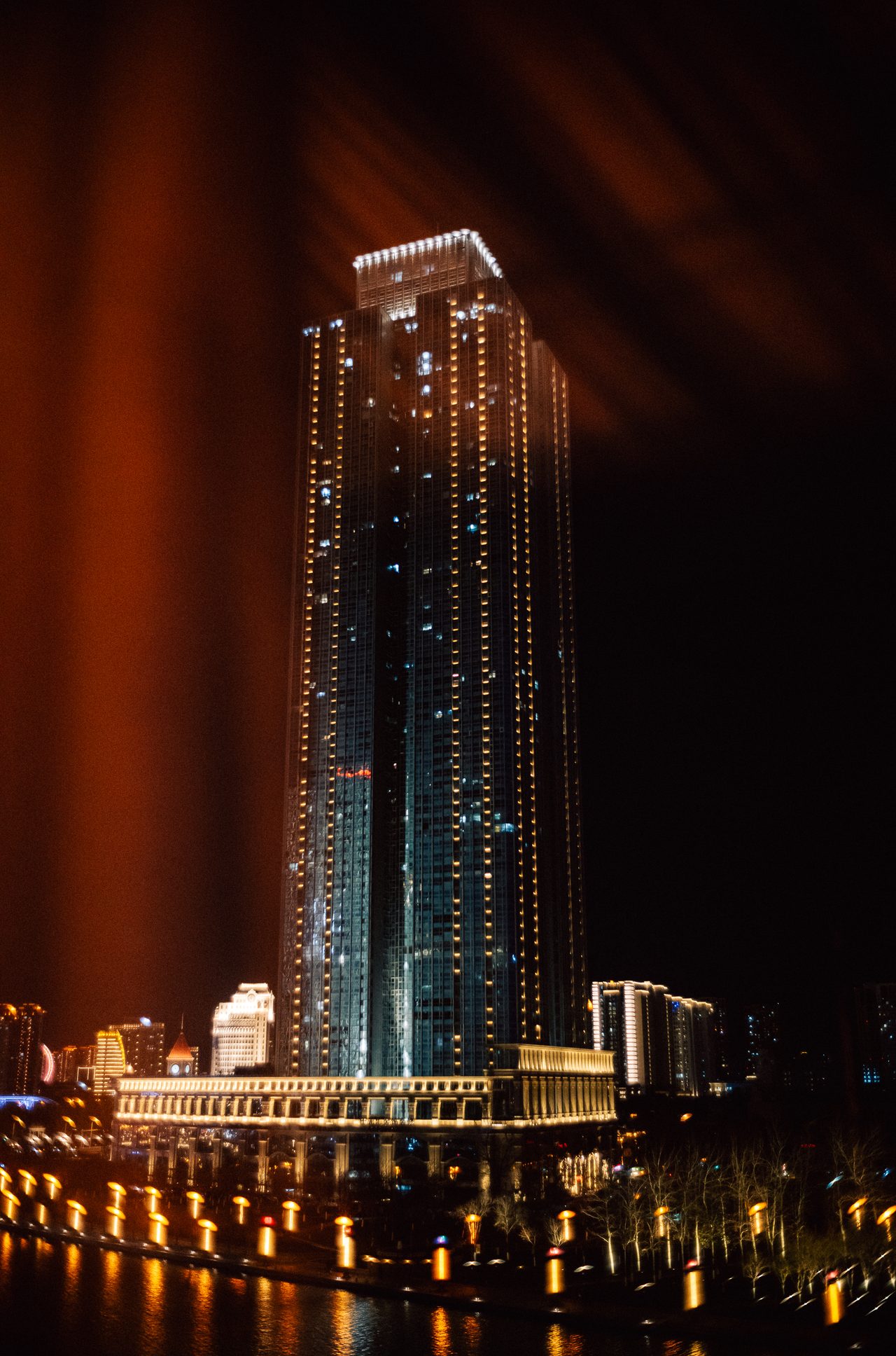 Ein beleuchtetes Hochhaus bei Nacht, eingerahmt von einem Vorhang.
