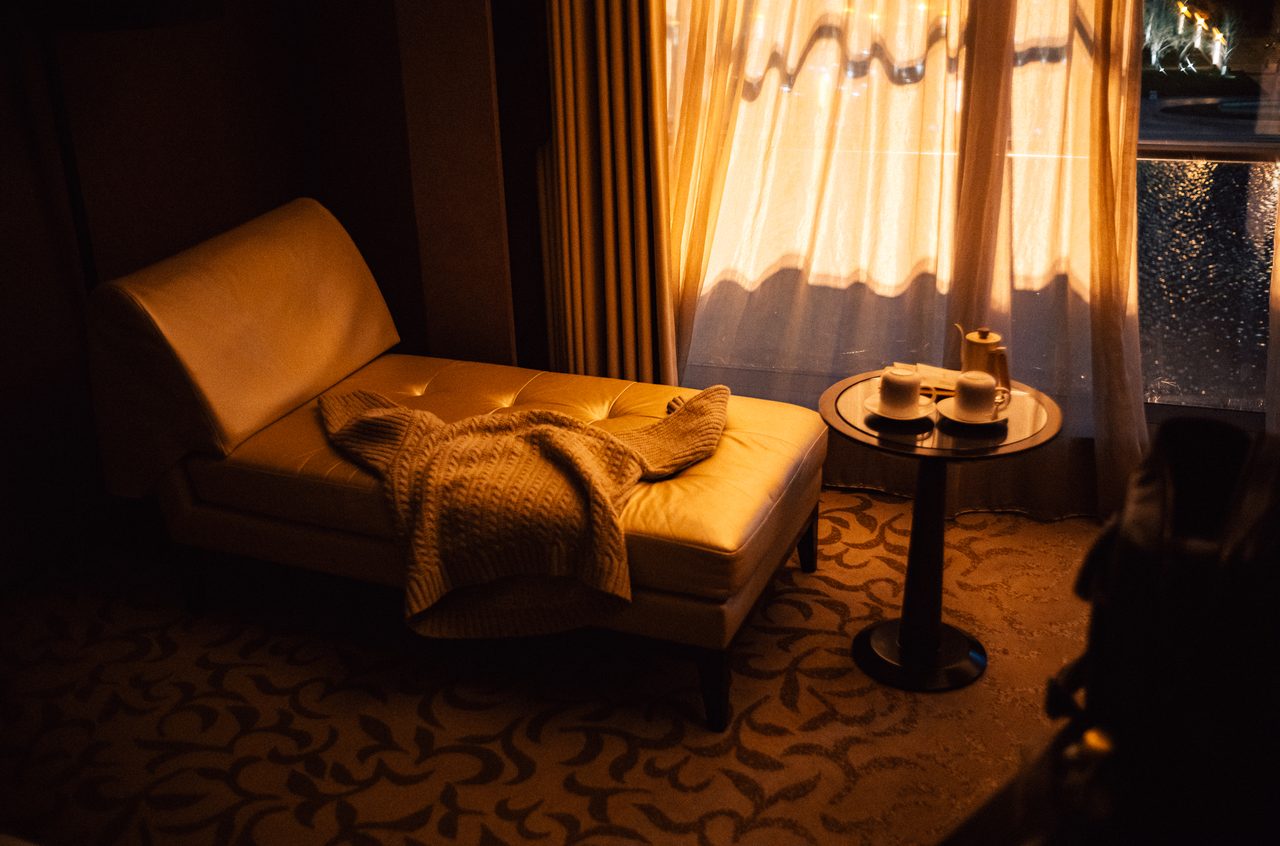 Sonnenlicht fällt auf eine Chaiselongue und einen Kaffeetisch im Hotelzimmer.