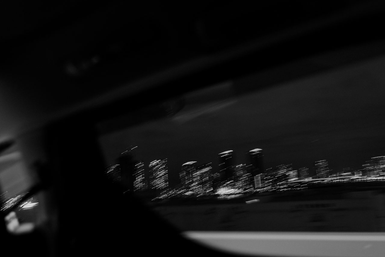 Verwischte Lichter einer nächtlichen Skyline durch ein Autofenster.