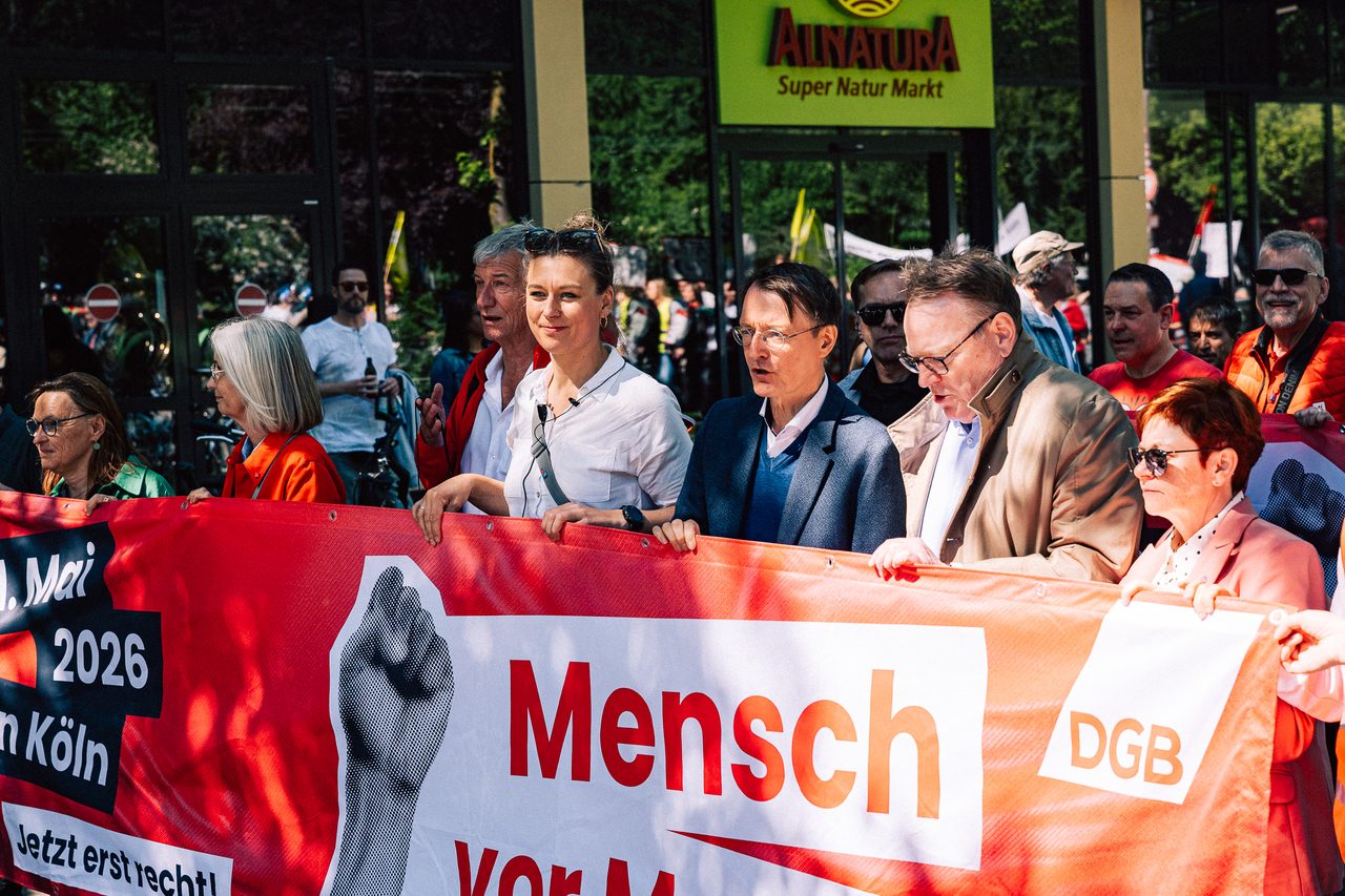 Menschen führen den Demonstrationszug mit einem roten DGB-Banner an