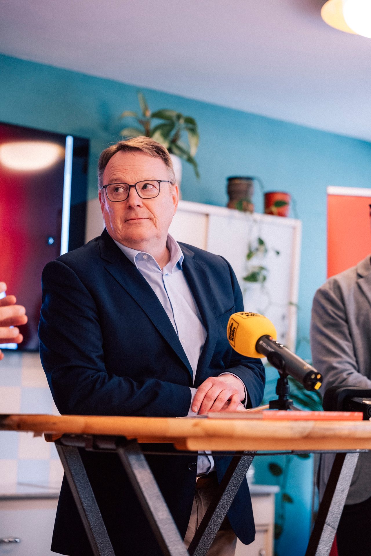 Thorsten Burmester hört an einem Stehtisch neben einem Mikrofon zu